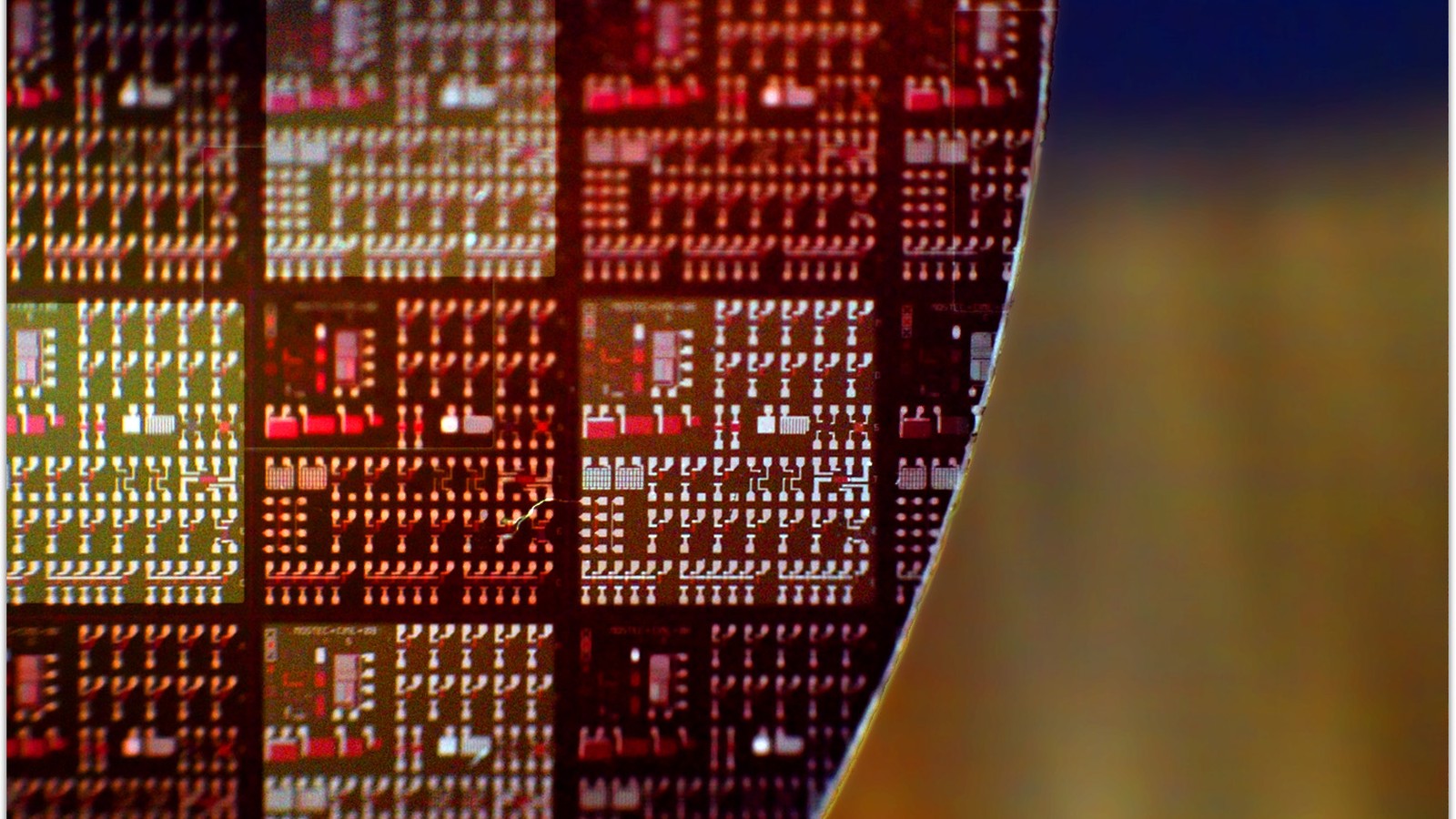 A close-up of the patterned surface and curved edge of a semiconductor wafer.