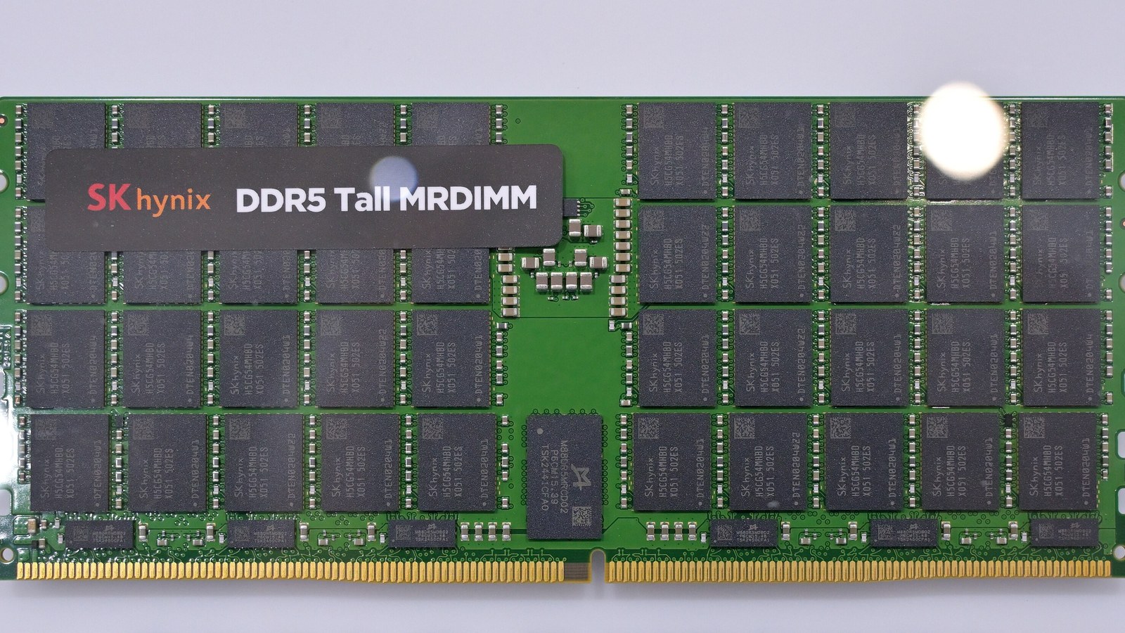 An SK hynix DDR5 Tall MRDIMM server memory module on a white display panel, rows of black memory chips on a green circuit board.