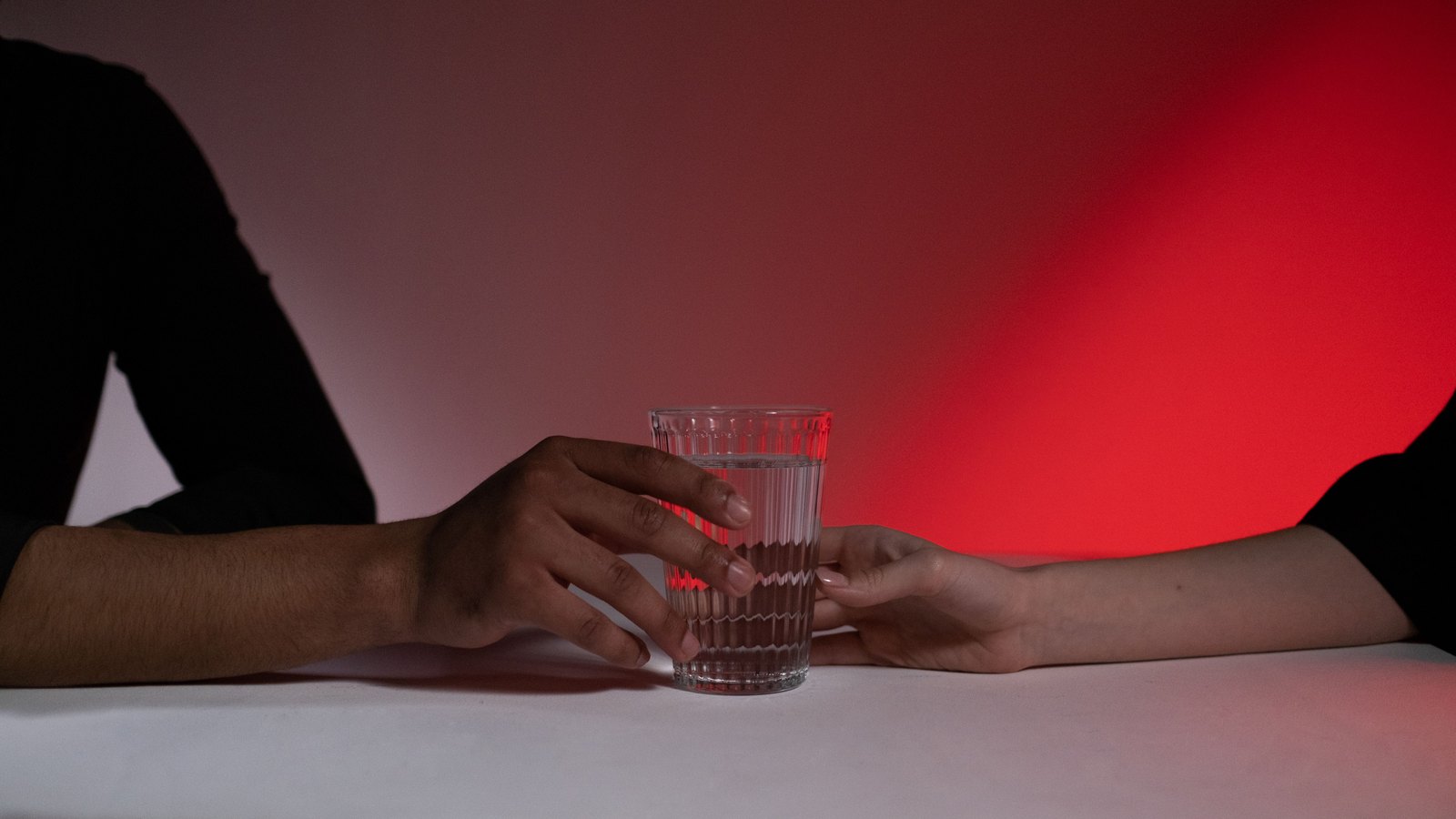 Two anonymous hands hold a clear glass of water against a red background, not a photograph of this advisory.