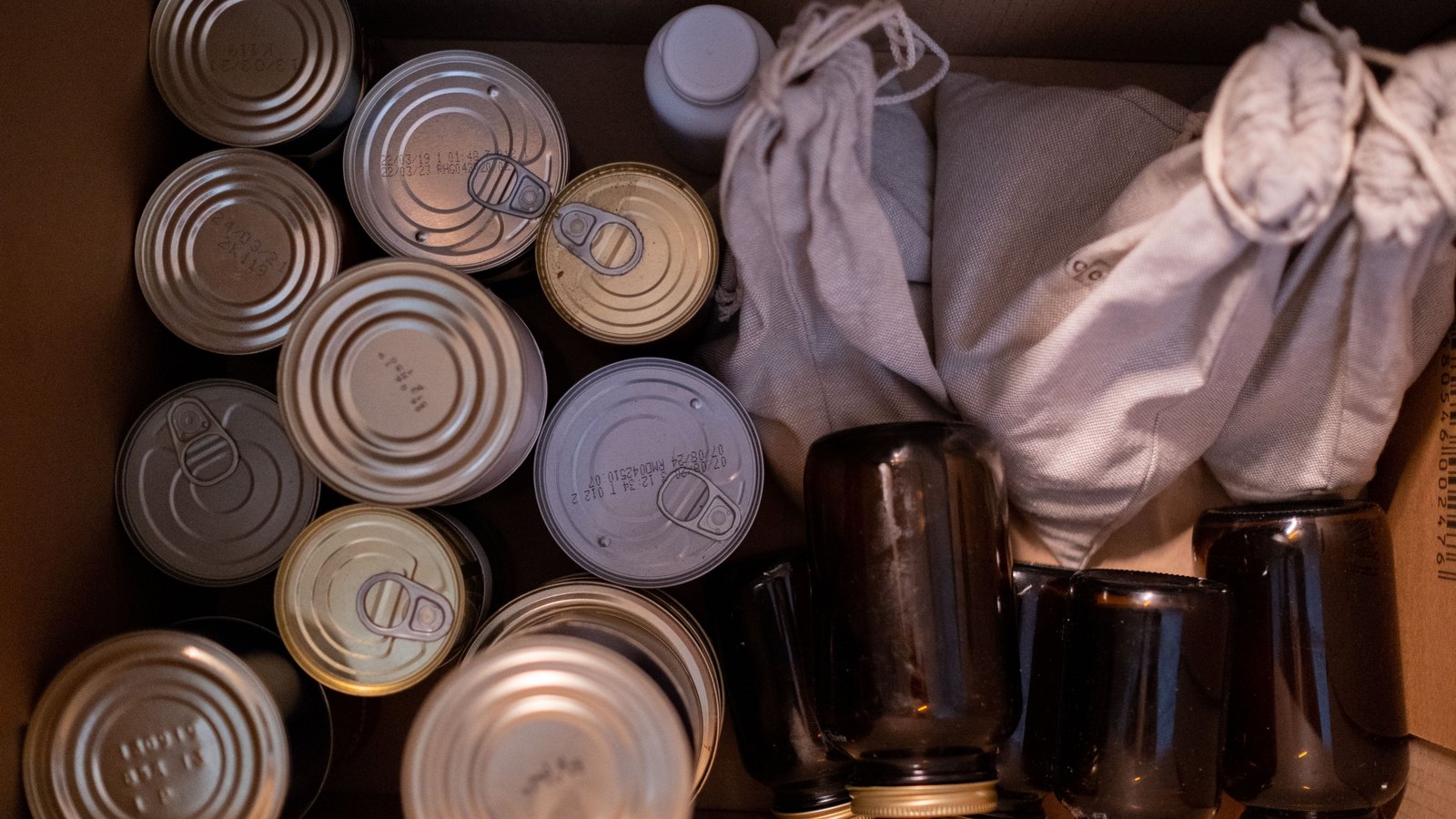 A cardboard box holds canned and jarred food supplies, not a photograph of the planned hub.