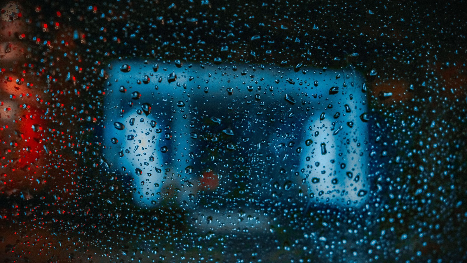 Blurred blue emergency lights seen through rain-streaked glass, not a photograph of this event.