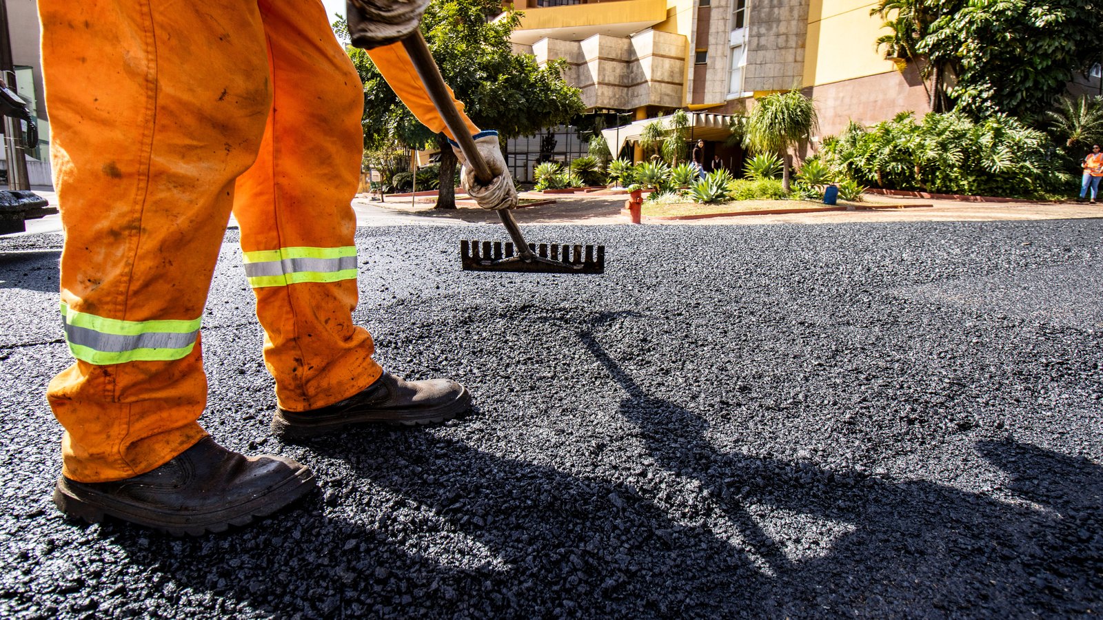 A road worker rakes fresh asphalt on a city street. Stock photo, not the Lehigh Acres project.