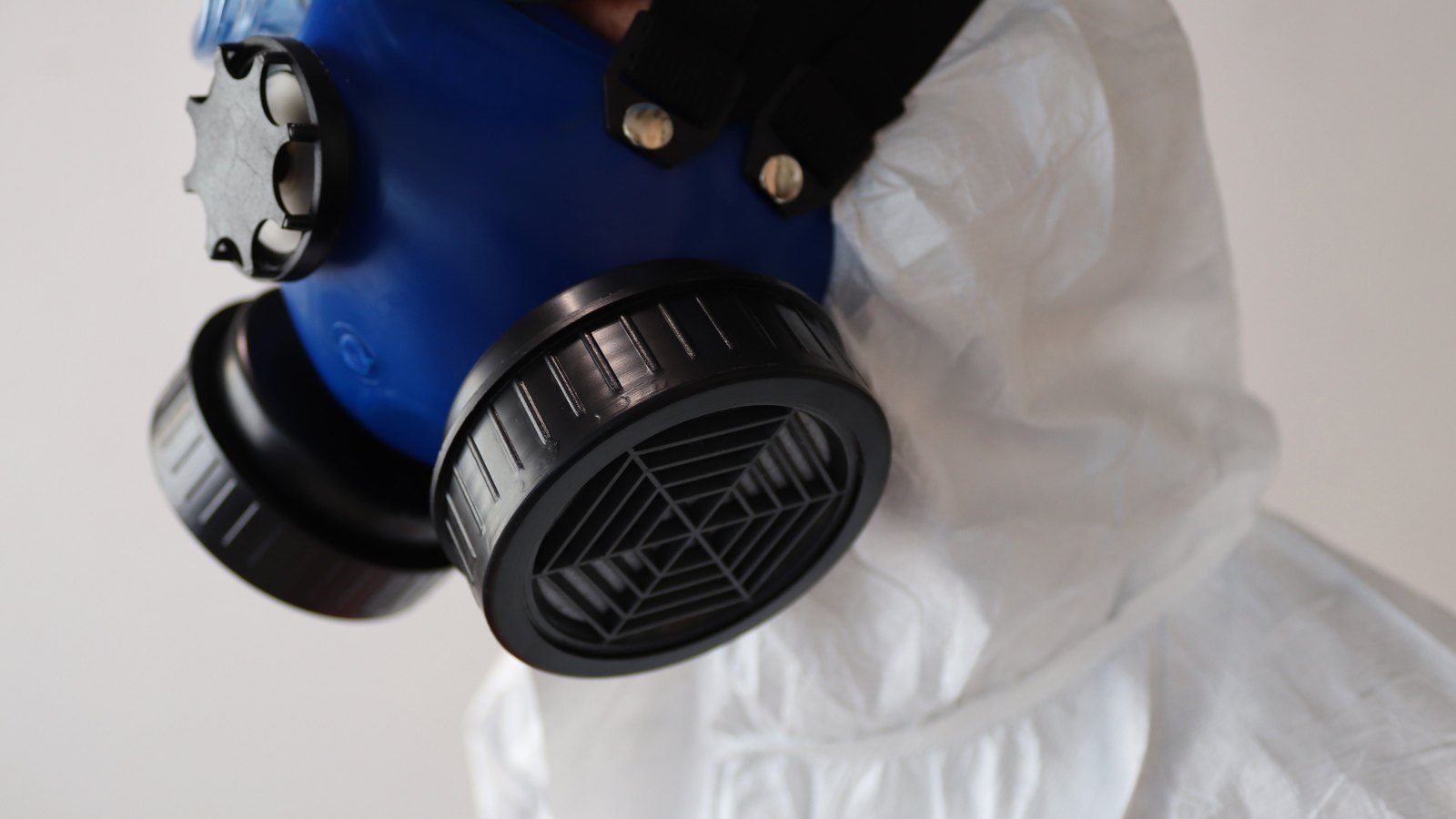 A close view shows a blue respirator and white protective suit, not a photograph of this spill.