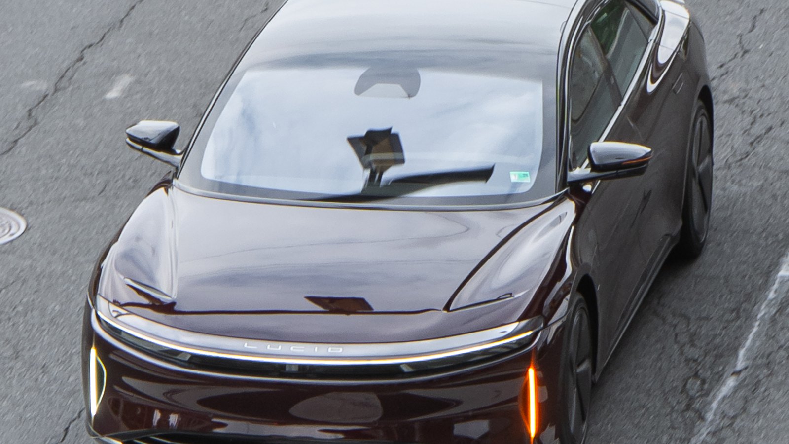A Lucid Air electric sedan driving on a city street.