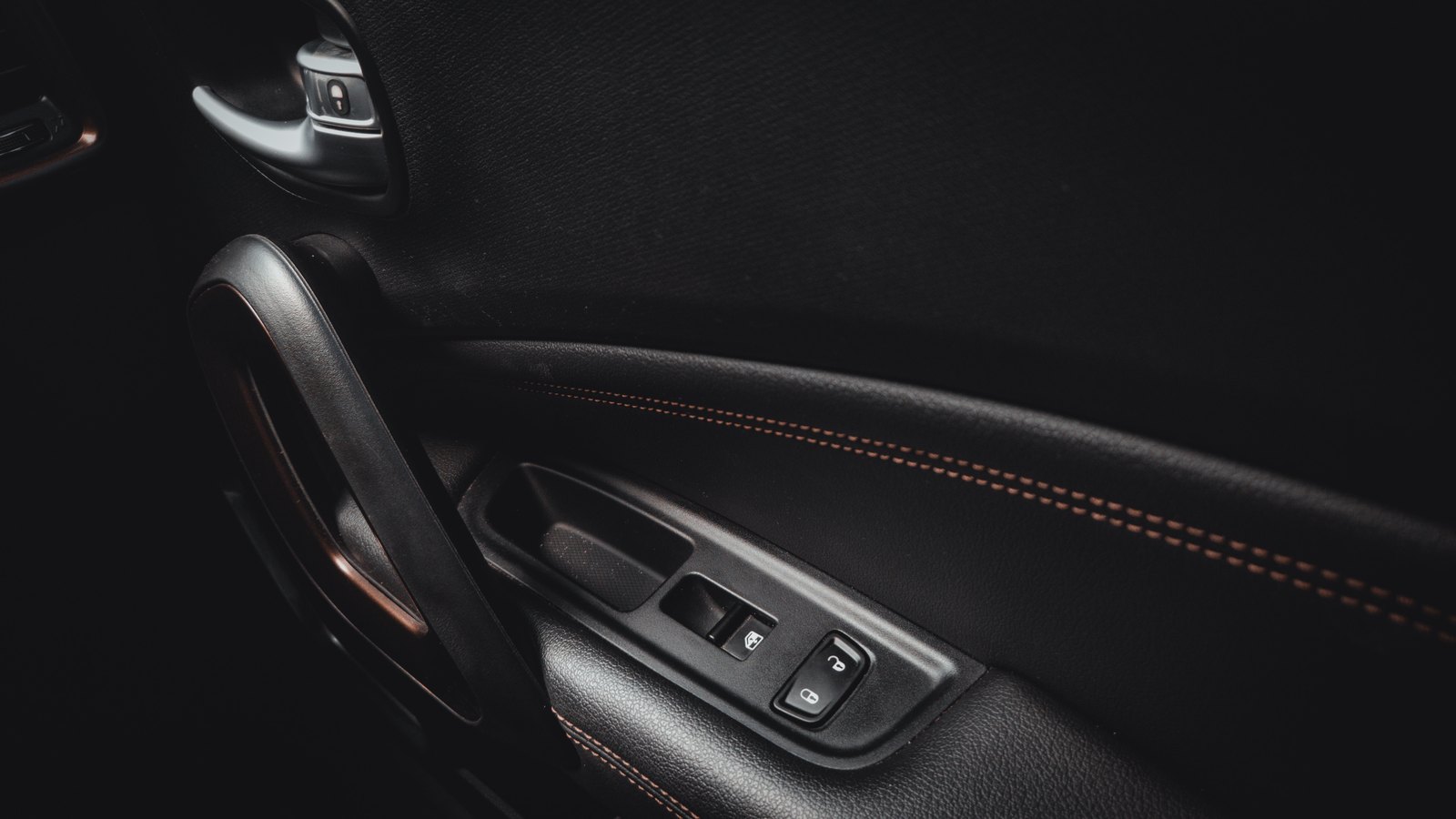 A dark car door interior with a handle and lock controls, not a photograph of this event.