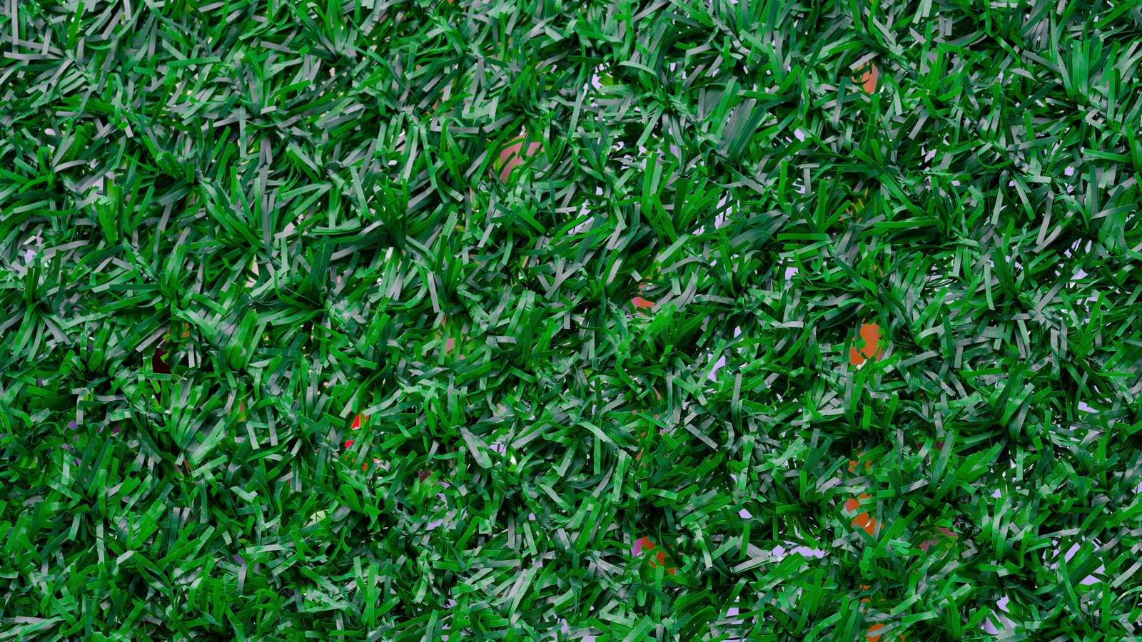 A close photograph taken straight down onto artificial turf, the flat green plastic blades leaning in every direction and filling the whole frame. A few small patches of the orange backing mat show through the gaps. No text, lettering, brand mark, person or place is in view.