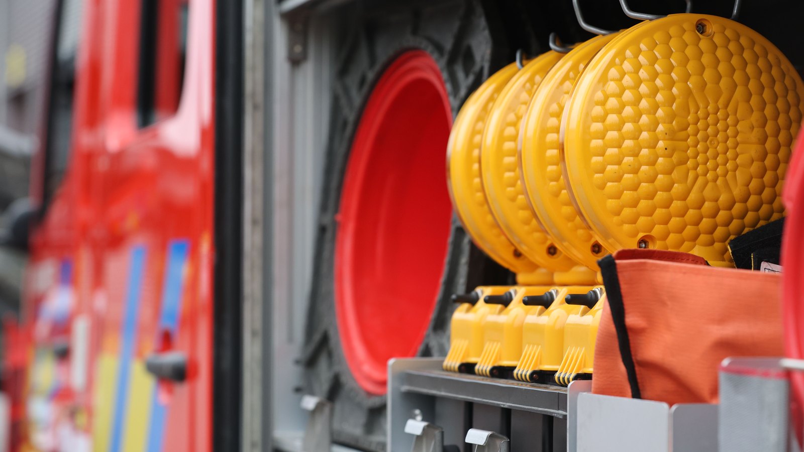 Amber warning discs and safety equipment in the side compartment of a red emergency vehicle, not a photograph of this event.