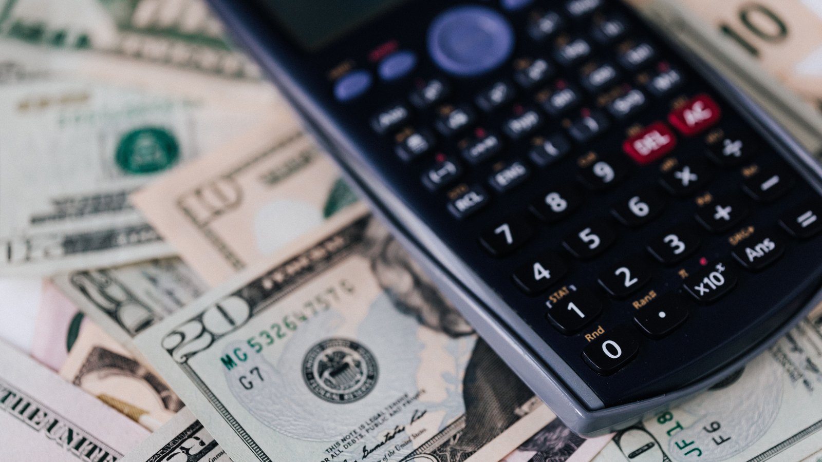 A calculator rests on a spread of United States dollar bills.
