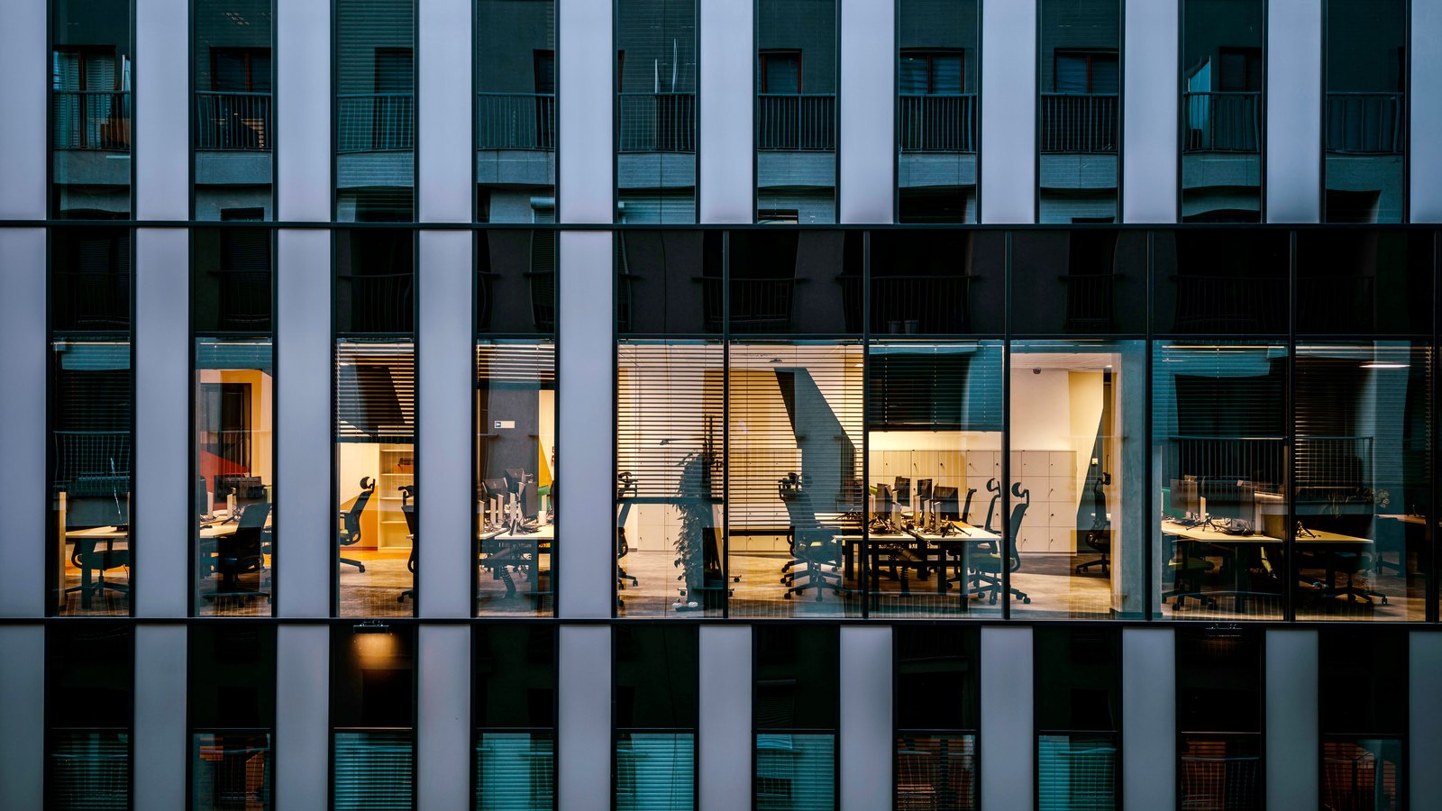 Illuminated offices seen through the windows of a modern commercial building.