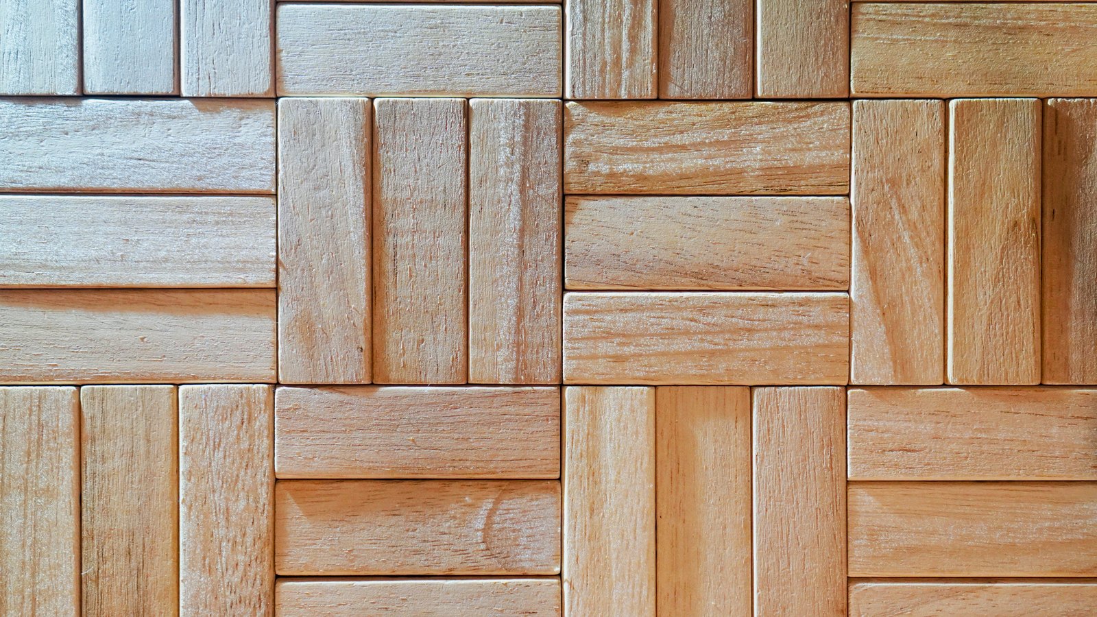 Pale wooden parquet filling the frame, square blocks each made of three or four narrow slats, laid so that every block runs at right angles to the ones beside it.