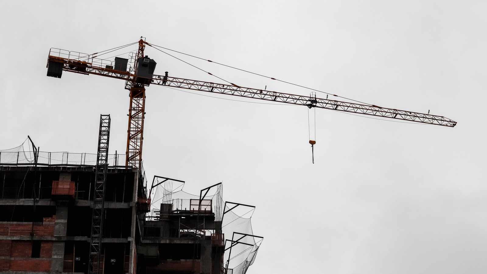 A tower crane extends above the concrete frame of a building under construction.