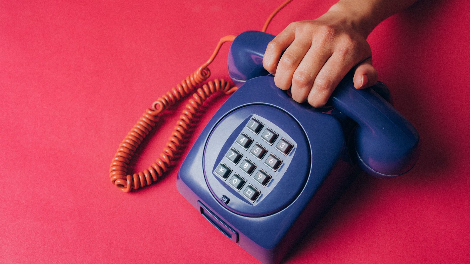 A hand lifts the receiver from a blue telephone, not a photograph of this search.