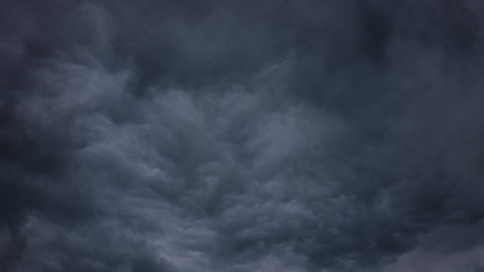 Dark grey storm cloud filling the frame, dense and low, with no horizon visible.