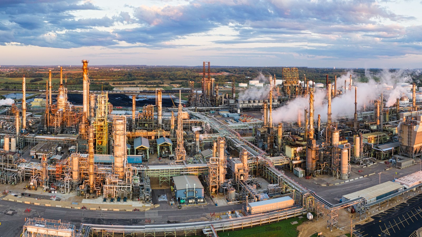 An oil refinery spreads across an industrial site beneath a wide sky.