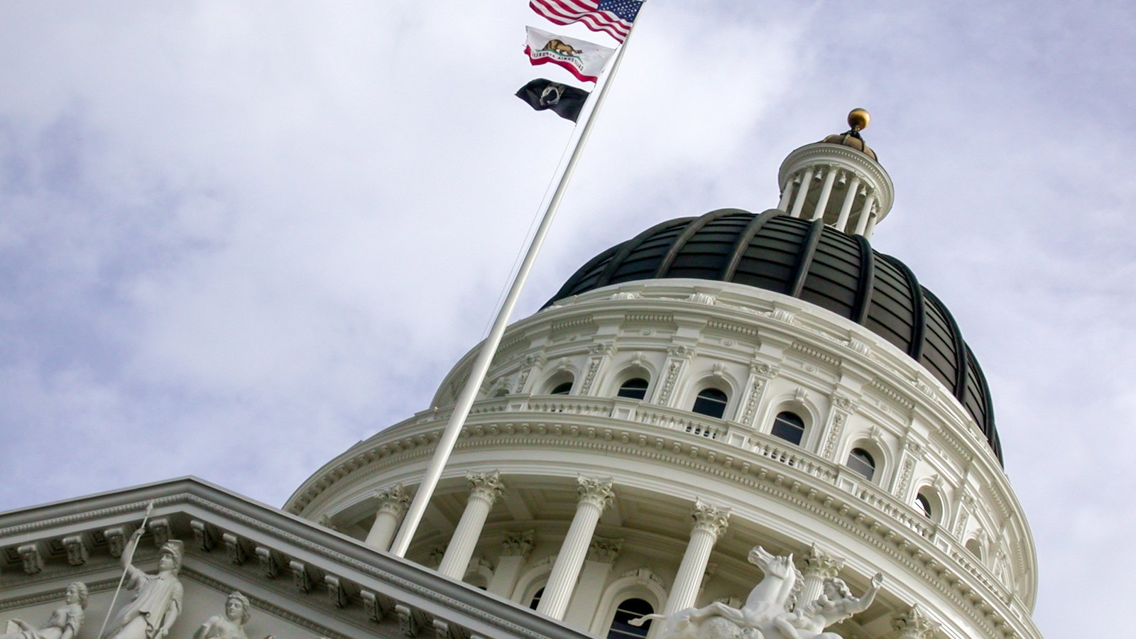 The dome of the California State Capitol beneath the United States and California flags.