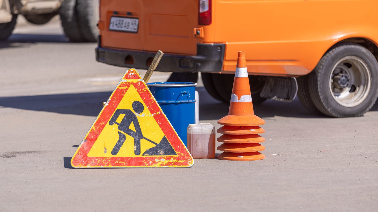 Traffic cones and a roadwork sign on an asphalt road.