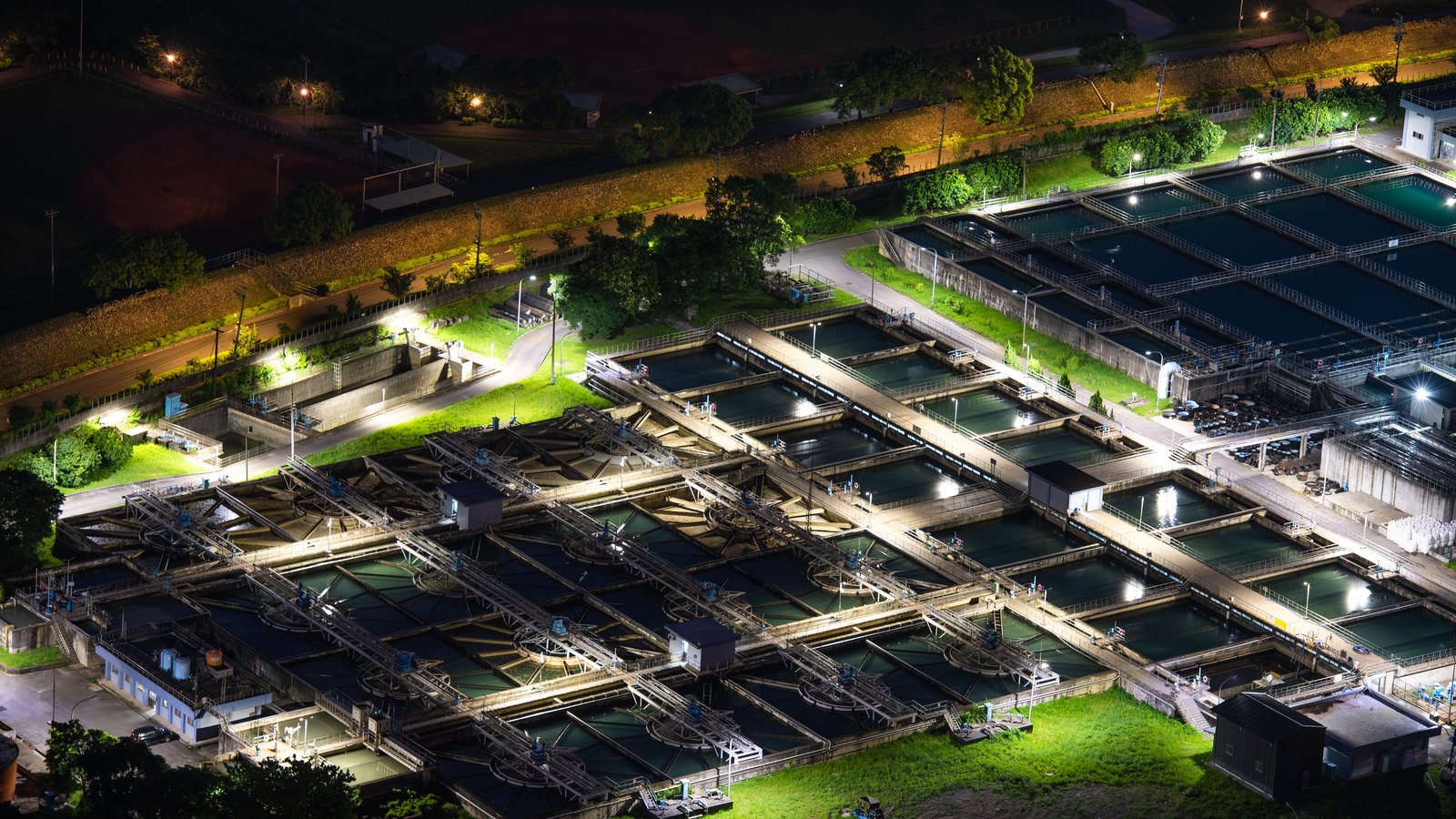 An illuminated water treatment plant viewed from above at night.