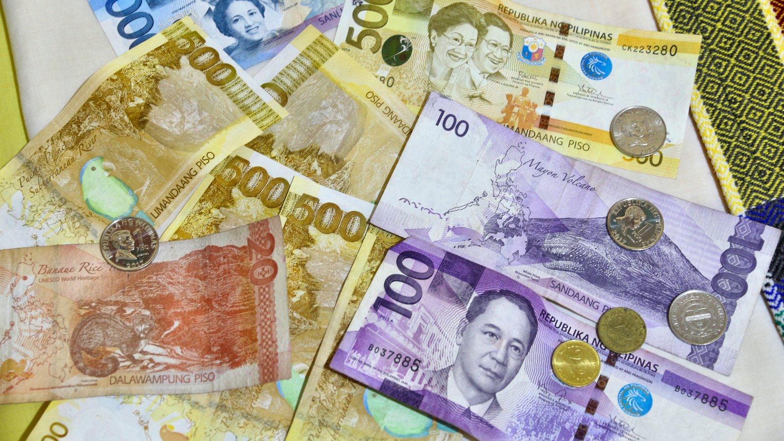 Philippine peso banknotes and coins arranged on a light surface.