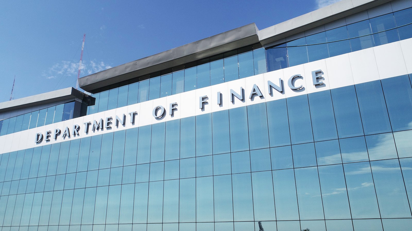 The Philippine Department of Finance name spans a blue glass facade in Manila.