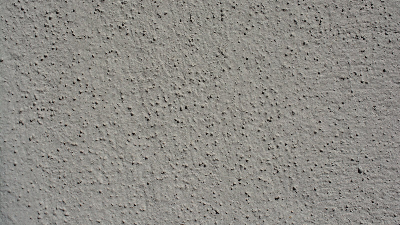 A close view of a grey rendered wall surface, finely pitted and evenly textured across the whole frame.