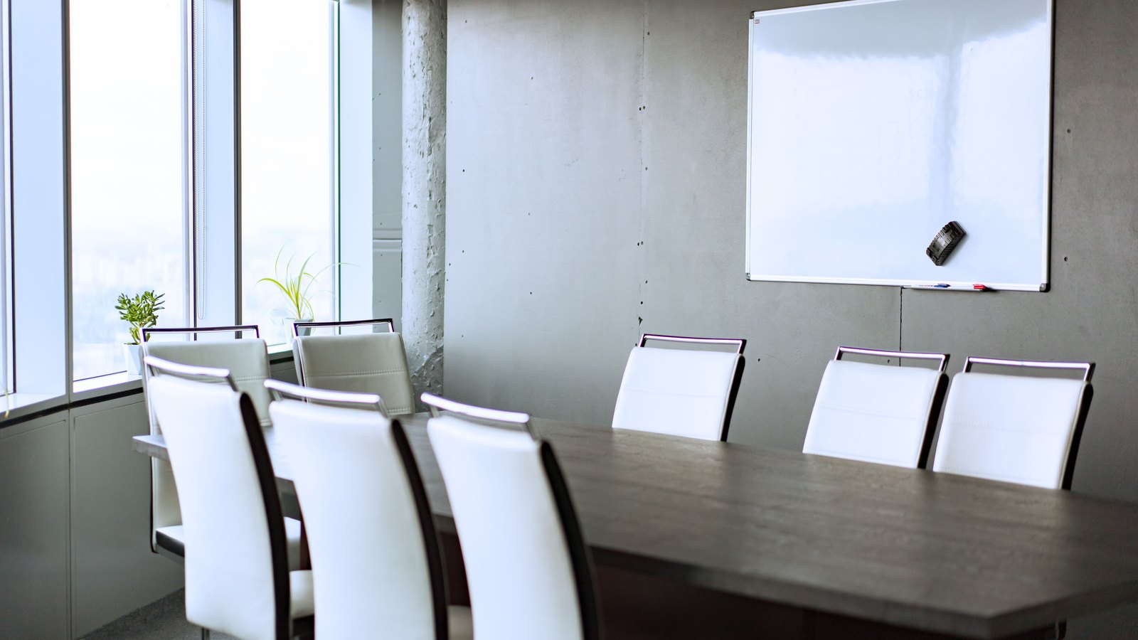 White chairs around a long table in an empty conference room.