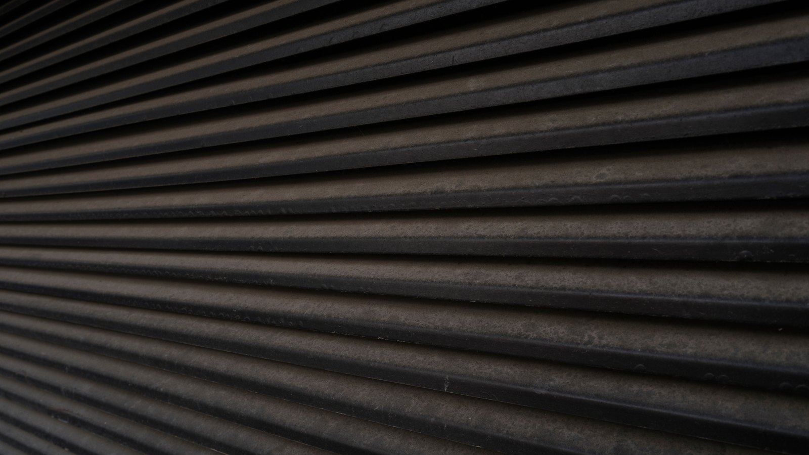 A photograph illustrating dense pattern of fine parallel grooves across a pale unglazed terracotta surface macro.
