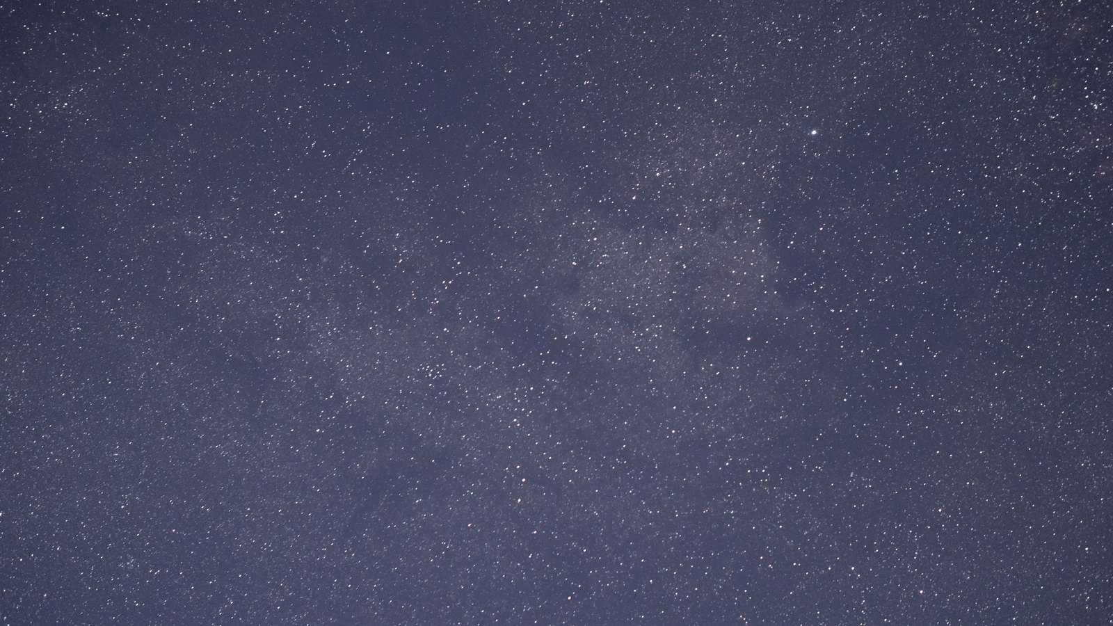 A full frame photograph of a night sky densely filled with faint white stars against a deep blue black background. No horizon, landscape, moon, aircraft, text or brand mark is in view.