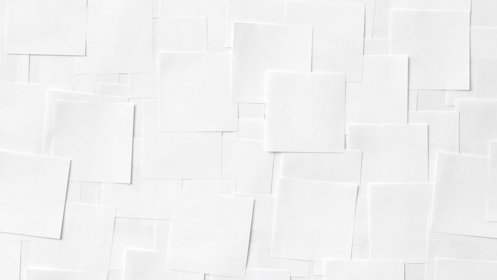 An overhead view of many blank white paper squares of similar size, overlapping in an irregular grid across the whole frame. No lettering, drawing, building, person or place appears. A generic paper texture, not a photograph of Royal Palm Square, of Fort Myers, or of any document in this story.