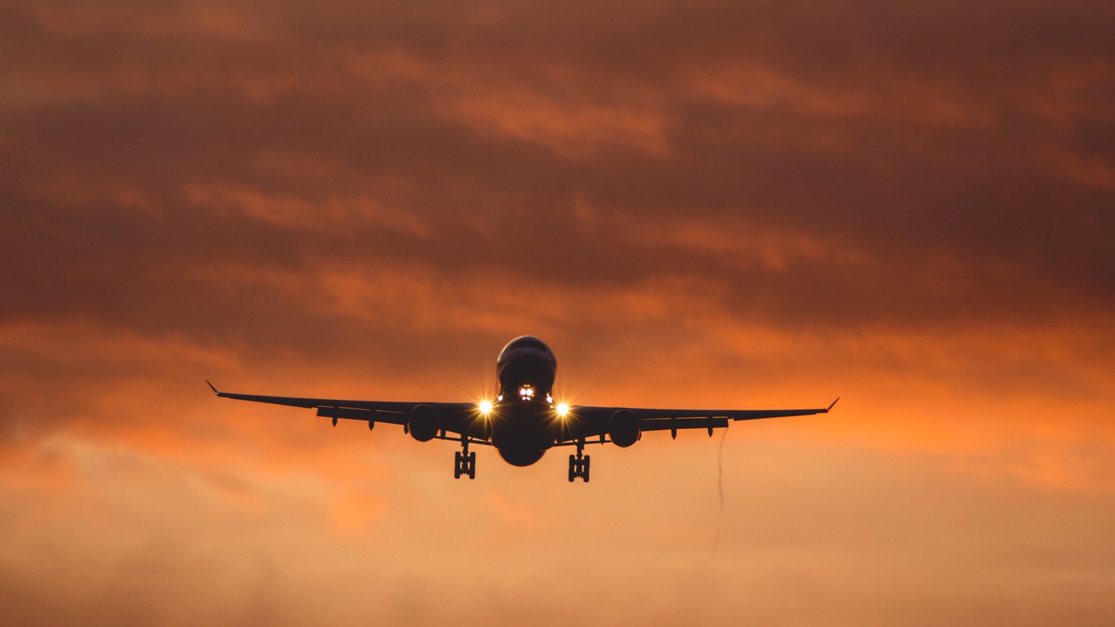 A passenger jet descends through an orange evening sky, not a photograph of this event.