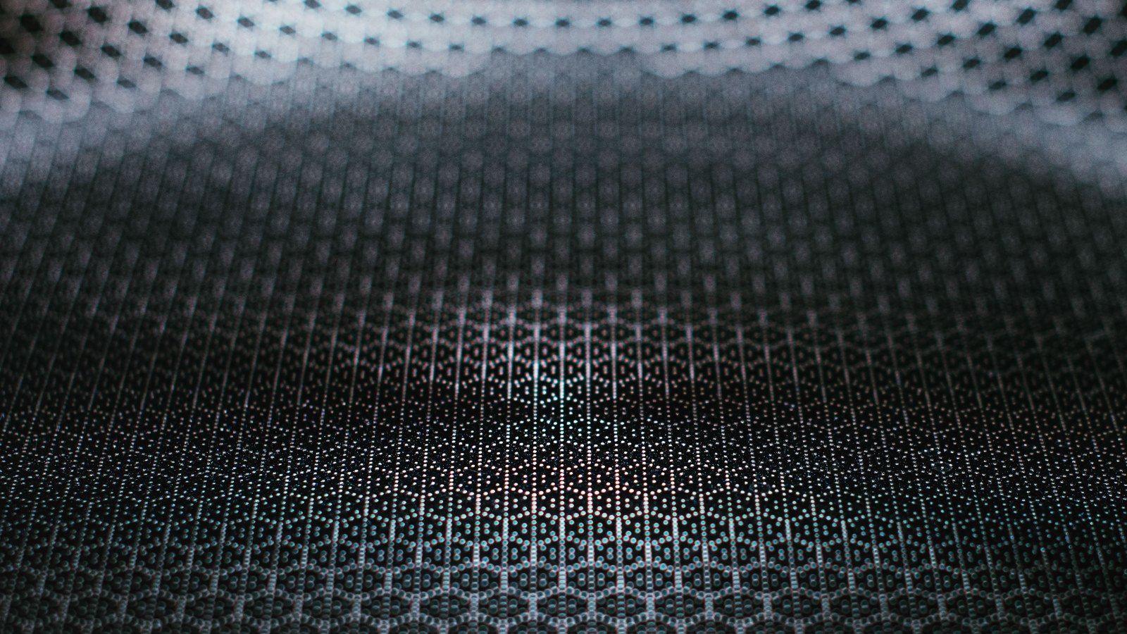 A dark curved surface covered edge to edge in a fine, regular grid of pale dots, sharp across the lower half and softening towards a lit band along the top.