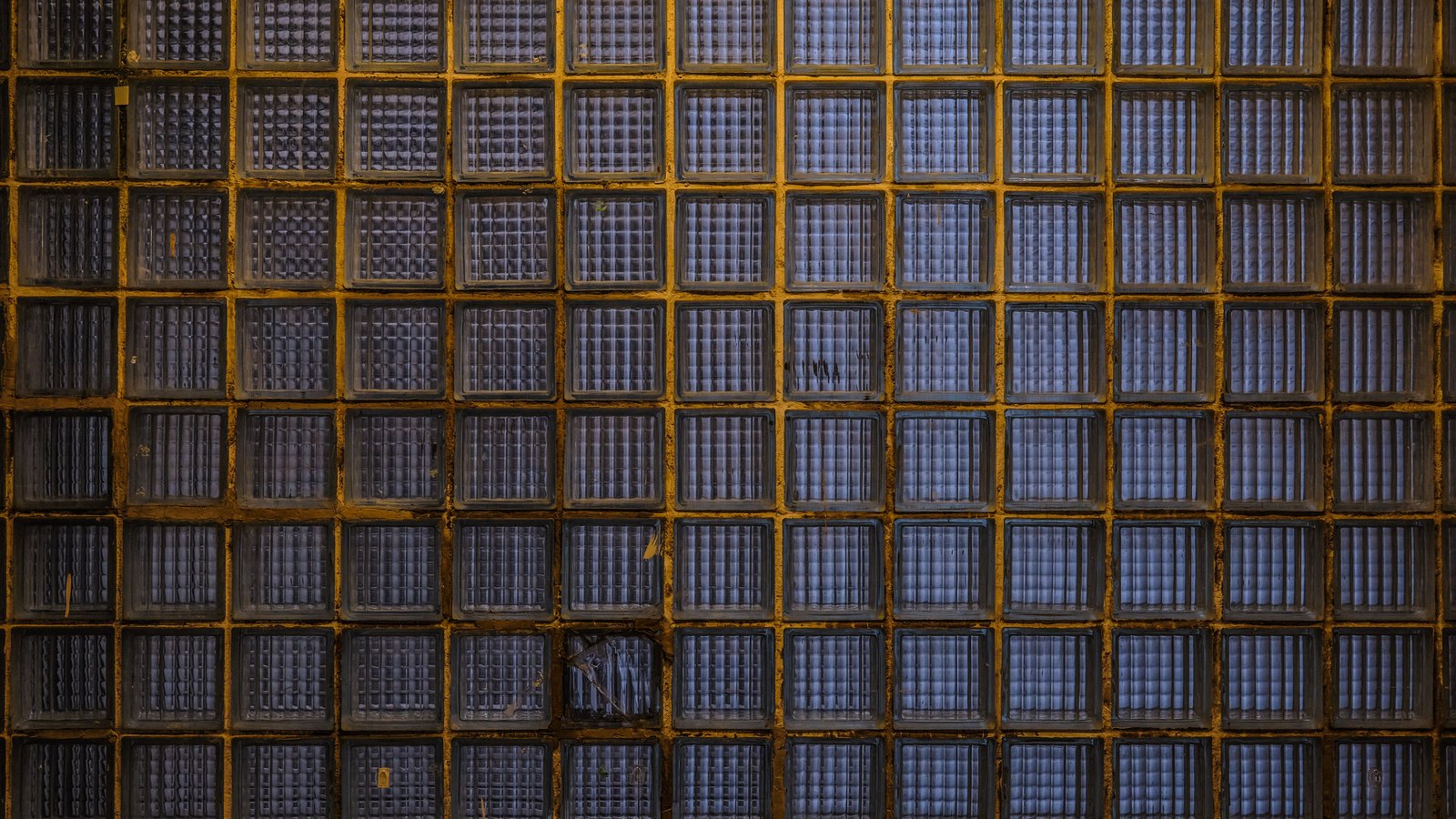 A photograph illustrating tight repeating grid of small square holes in pale woven rattan cane webbing filling the entire frame macro no chair no furniture no wooden frame.