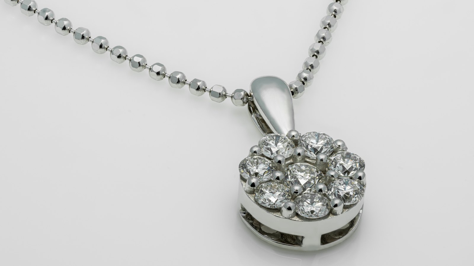 A diamond pendant on a plain silver chain against a white background.