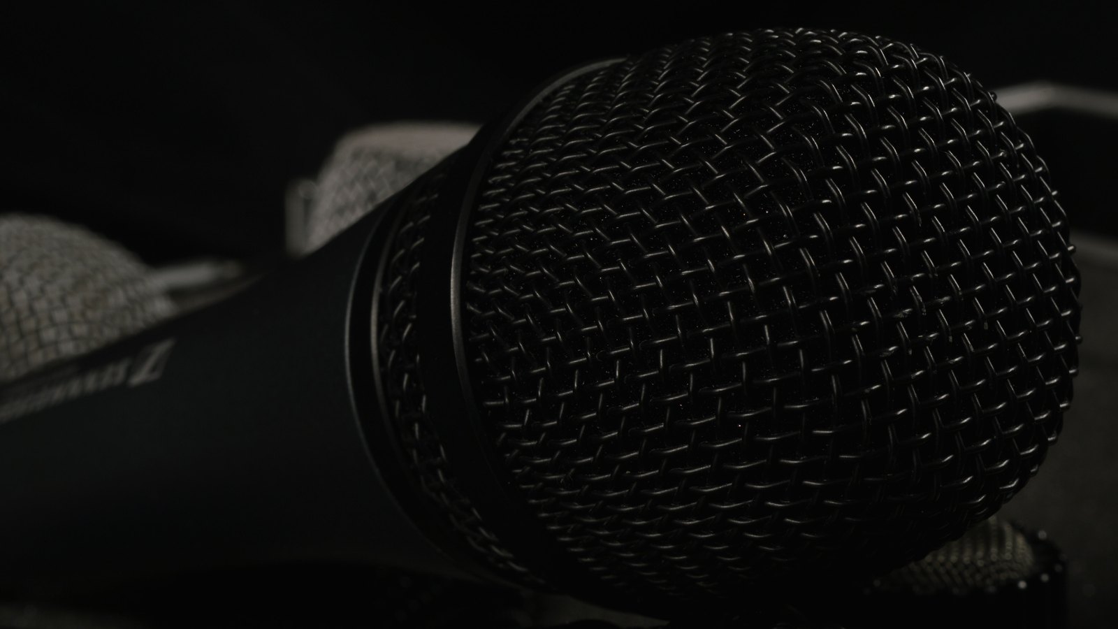 A close view of the black mesh head of a handheld microphone.
