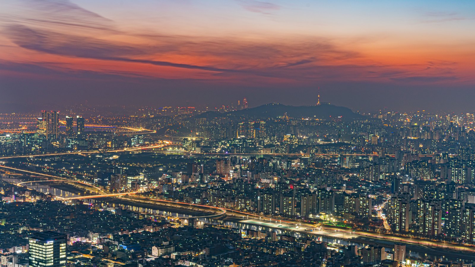 Seoul's illuminated cityscape and Han River at dusk.