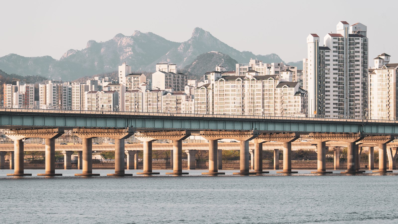 Apartment towers line the Han River beneath mountains in Seoul.