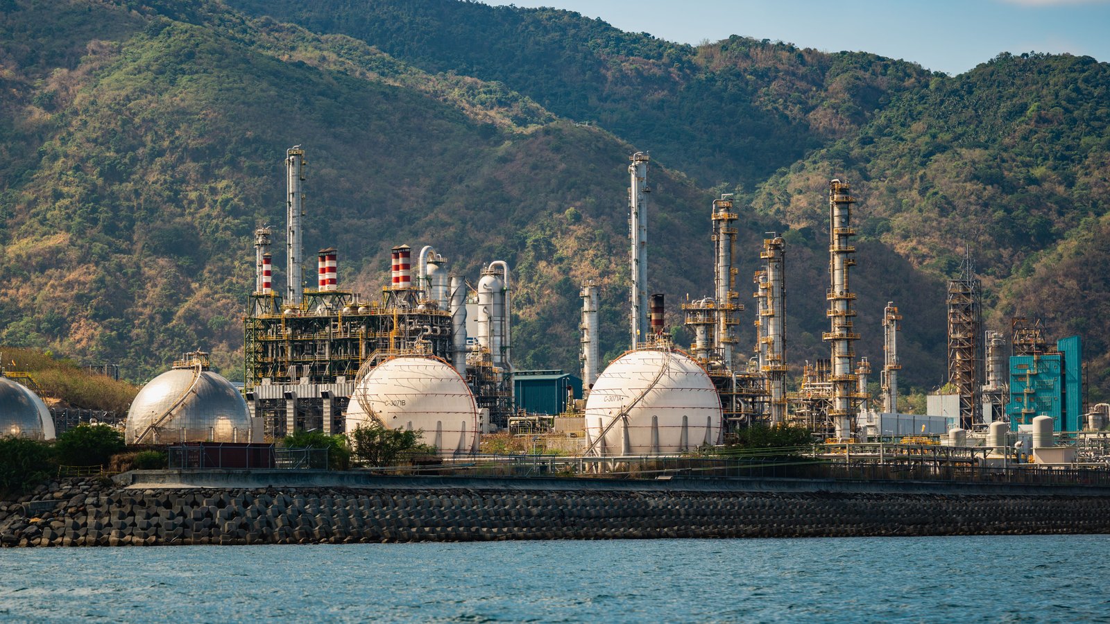 An oil refinery with storage tanks beside water, not a photograph of the inflation release.