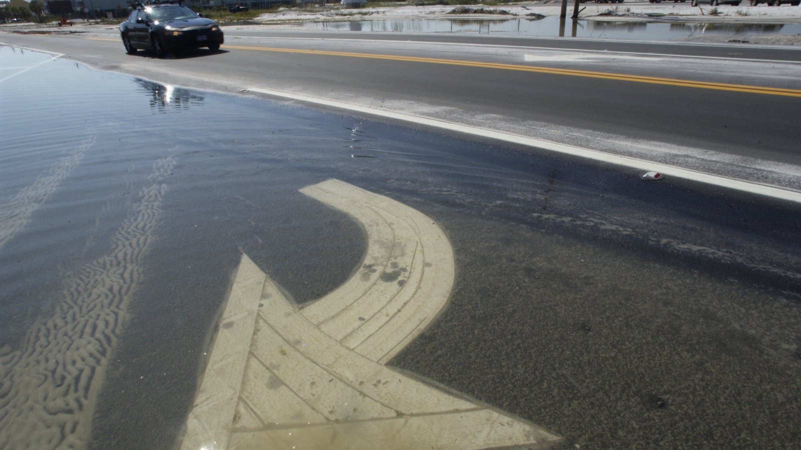 Standing water covers a painted turn arrow beside a Florida road, not a photograph of this advisory.