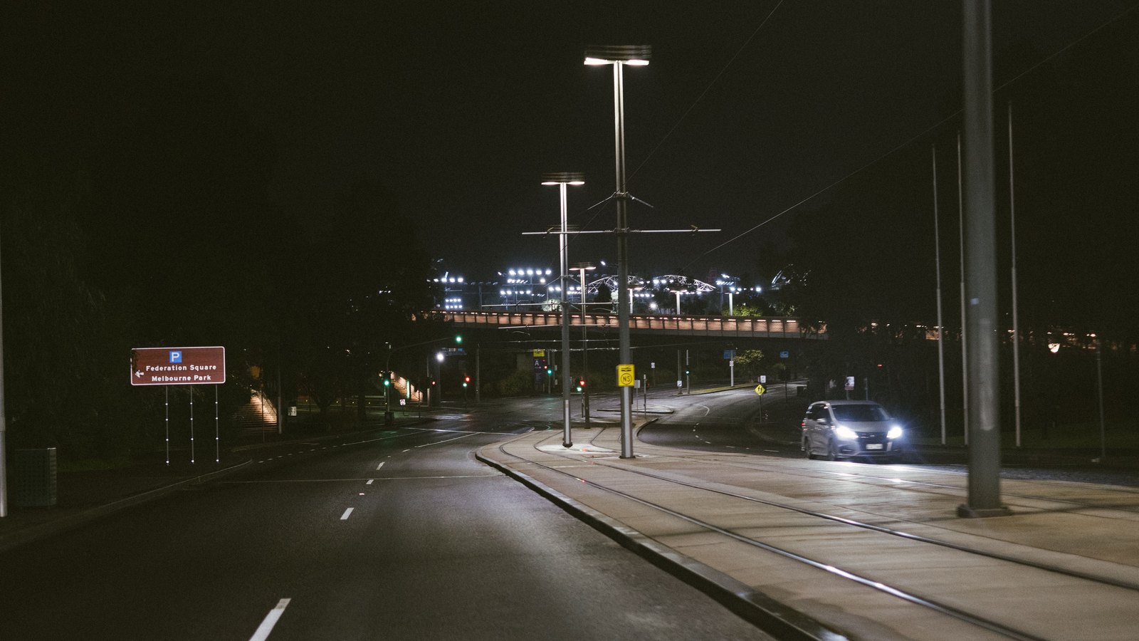 A dark multi-lane road at night with distant car headlights.