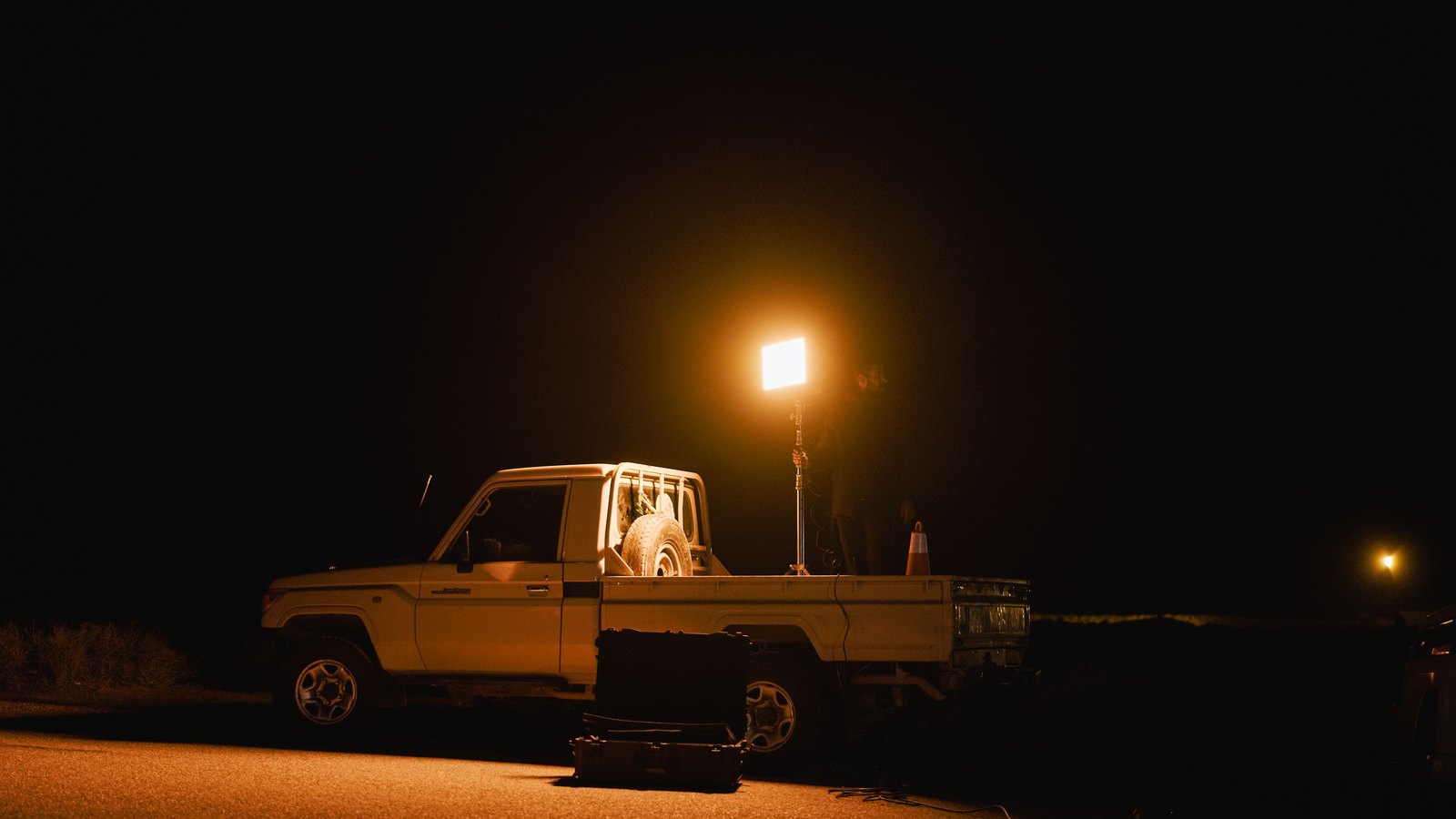 A pickup and portable work light illuminating a dark roadside, not a photograph of this event.