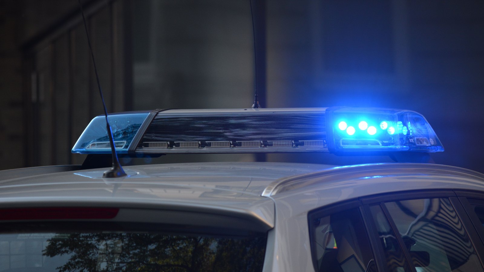 A police car with blue lights flashing on a street at night.