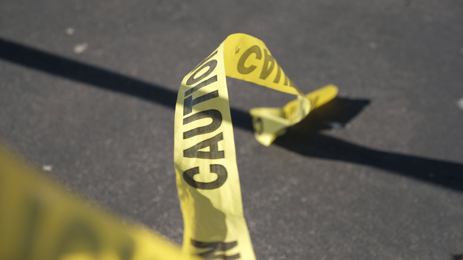 Yellow police caution tape stretched across pavement.