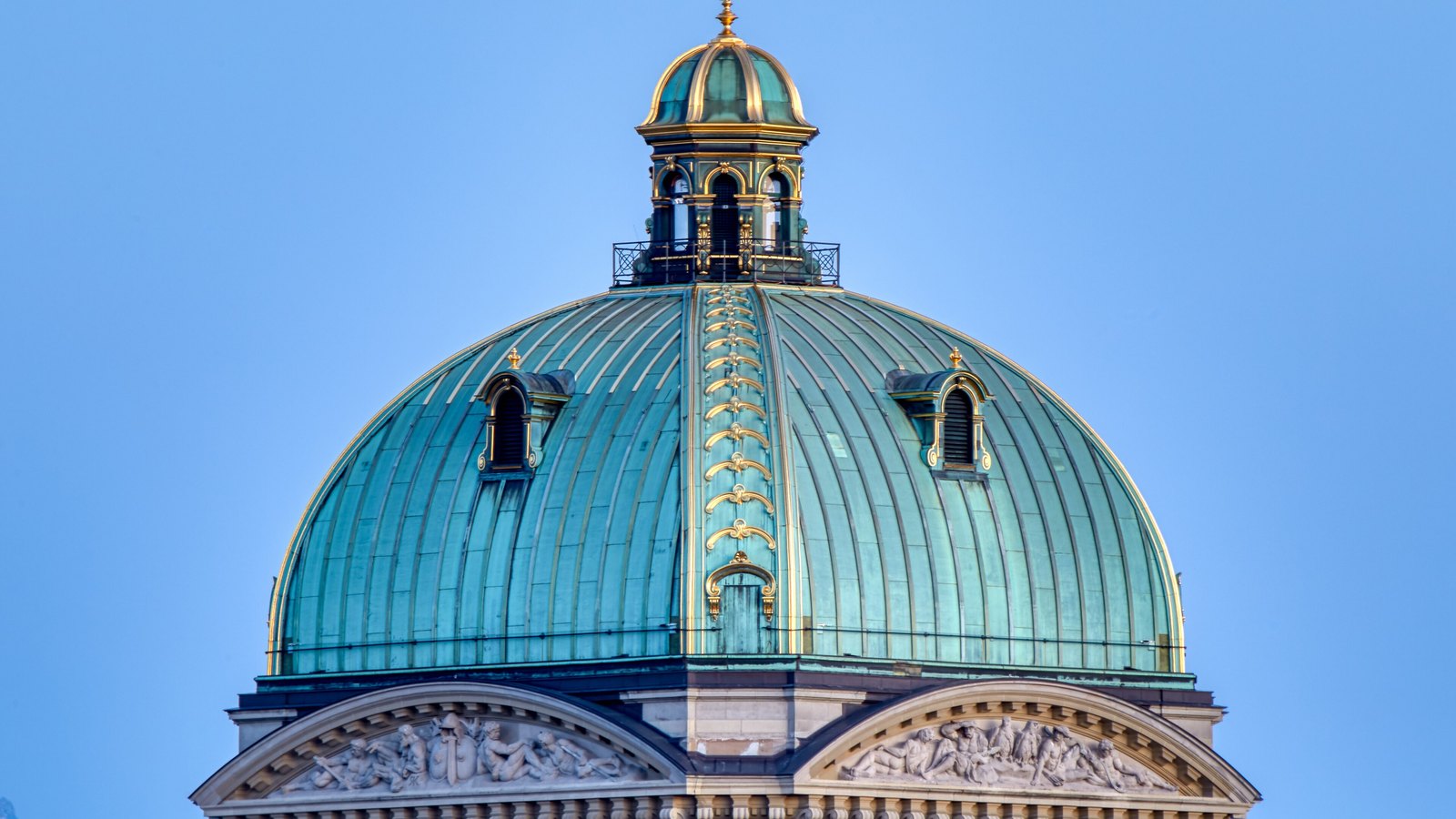 The copper-clad central dome of the Swiss Federal Palace in Bern against a clear sky.
