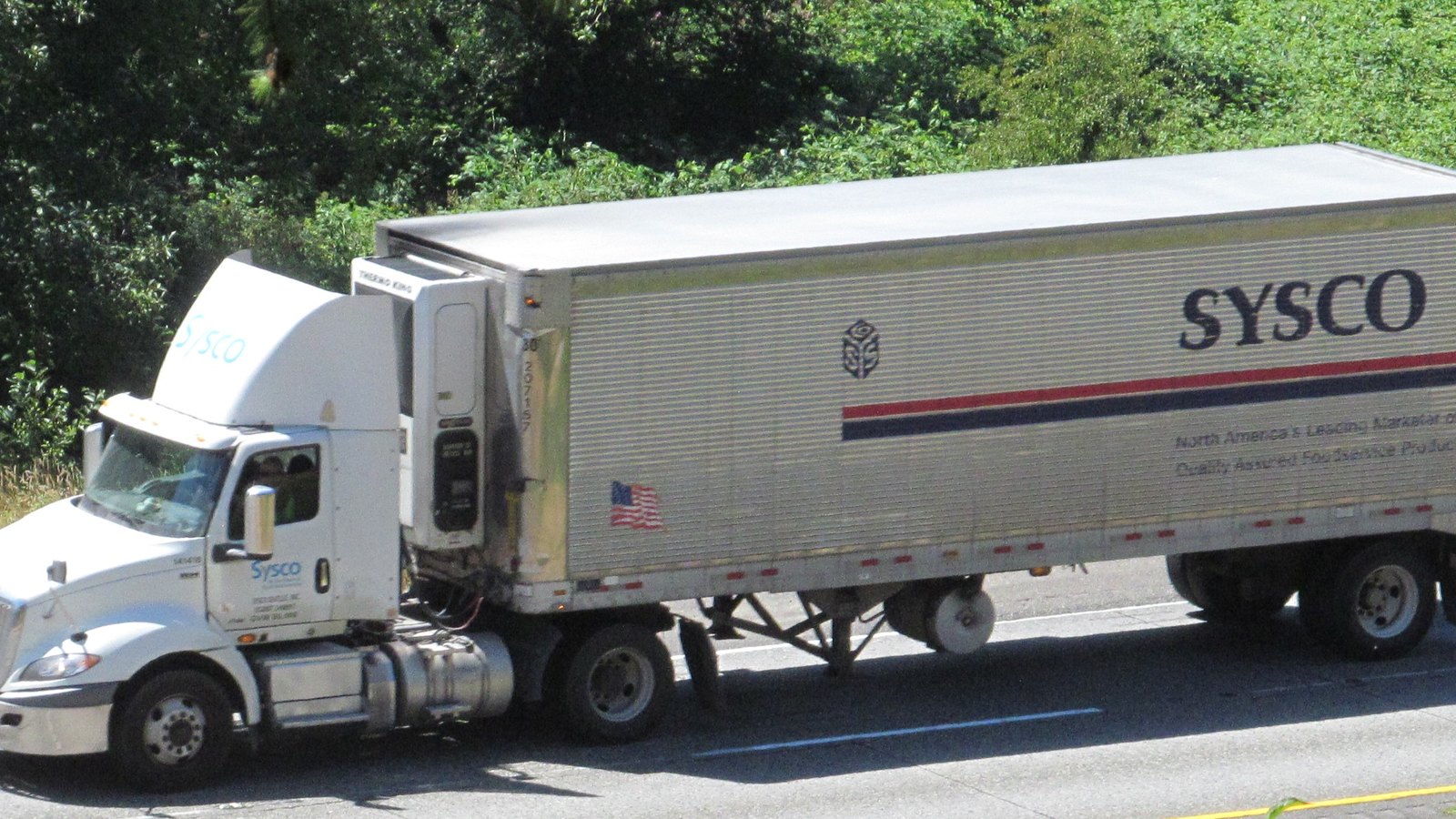 A Sysco semi truck traveling on a highway.