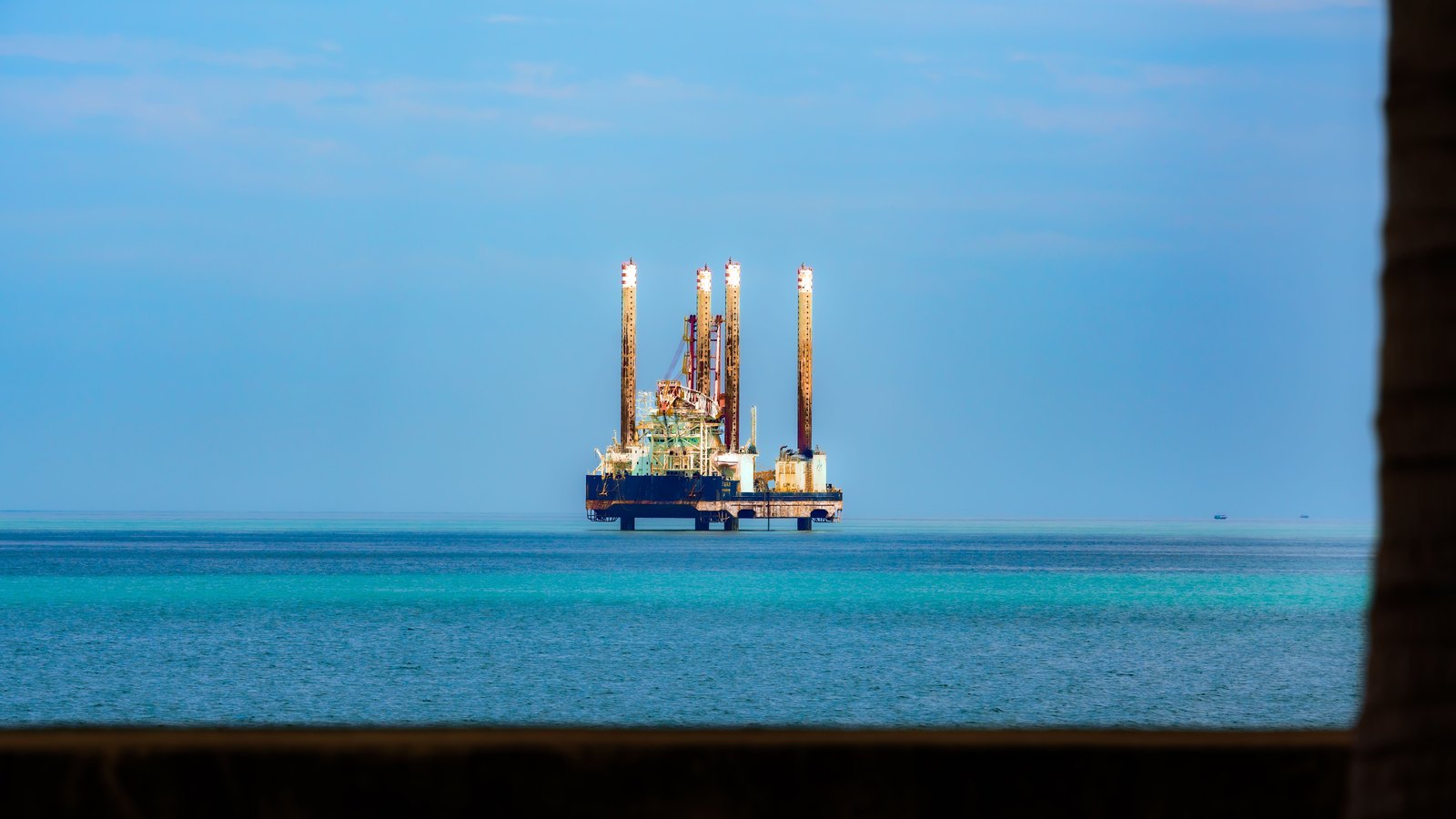 An offshore drilling platform sits in calm blue water, not a photograph of the acquired assets.