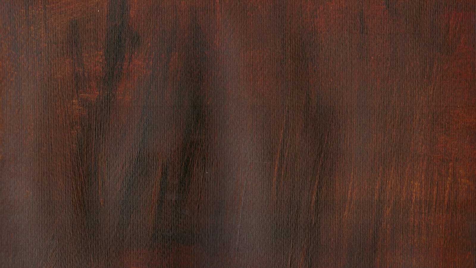 A close photograph of dark red-brown stained hardwood, the grain running vertically in bands of deeper and lighter colour, filling the frame with no edge, marking or hardware in view.