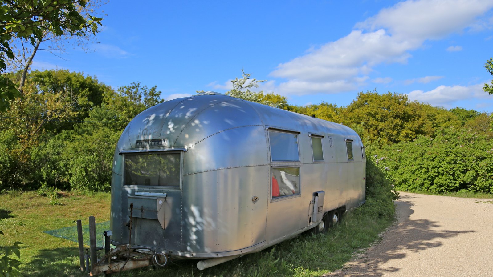 An Airstream travel trailer parked beside a country road.