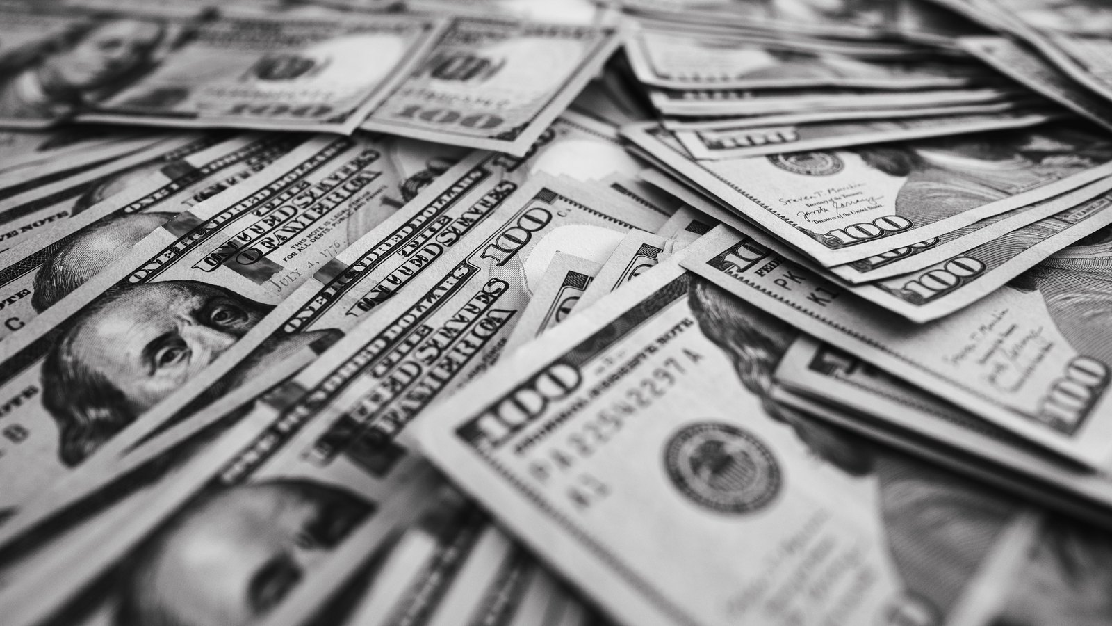 US one hundred dollar notes arranged across a surface.