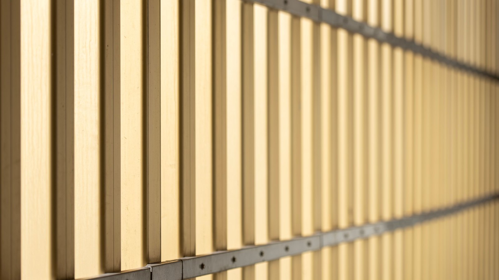 A photograph illustrating tight repeating pattern of narrow parallel flutes in pale ribbed glass filling the frame macro no text no window frame.