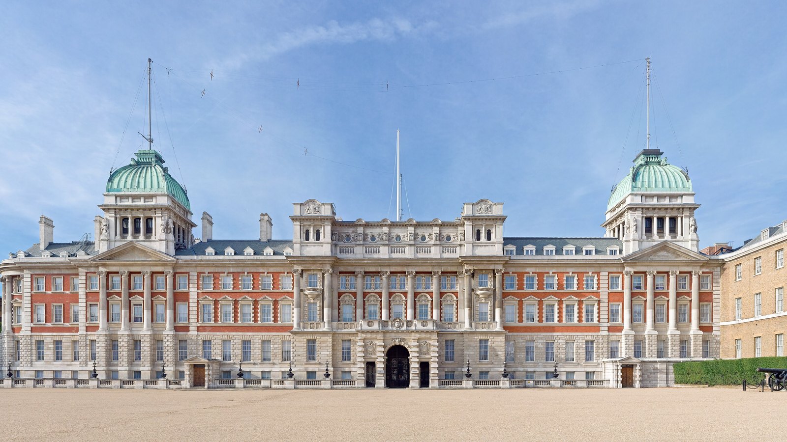 The red brick and pale stone Admiralty Extension seen across Horse Guards Parade under a blue sky.