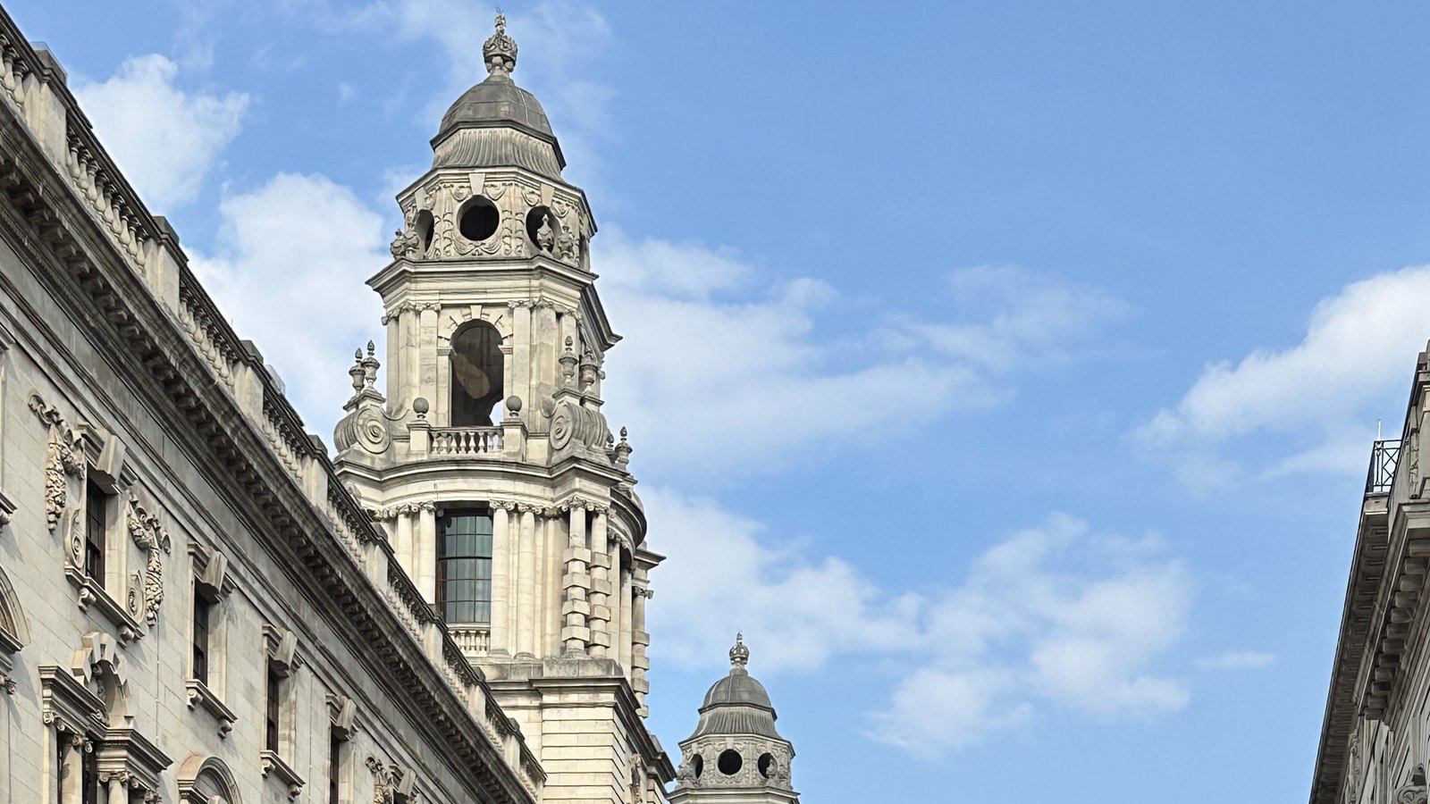 The domed corner towers of Government Offices Great George Street in Westminster, the building that houses HM Treasury and HM Revenue and Customs, against a blue sky.